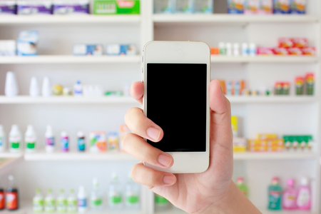 hand holding smart phone in pharmacy drugstoreの写真素材