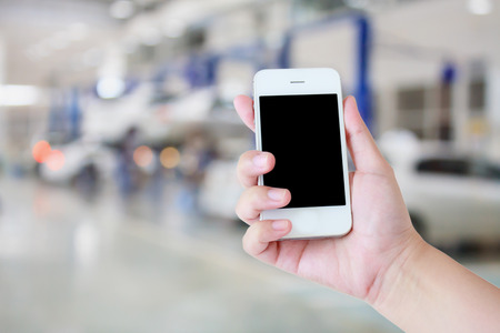 hand hold smartphone with car repair service center backgroundの写真素材
