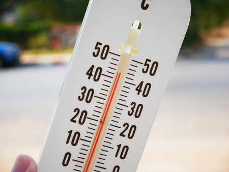 hand hold thermometer showing temperature in degrees Celsius, Hot temperatureの写真素材