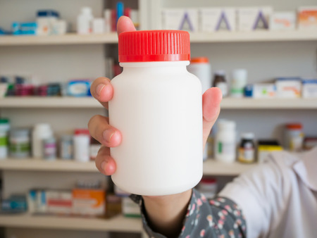 Female pharmacist hold medicine bottle on her hand in the pharmacy storeの写真素材