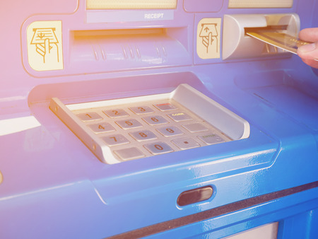 female hand inserting ATM card into ATM bank machine to withdraw moneyの写真素材