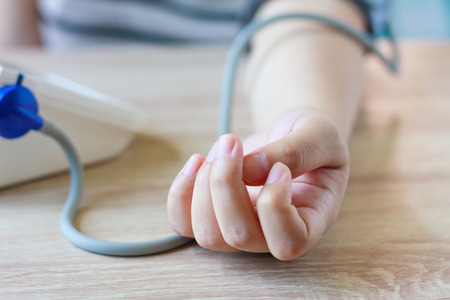 Woman using digital blood pressure monitor to measures her blood pressure