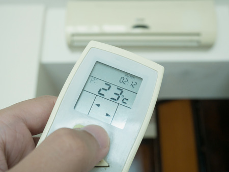 Hand hold remote control with conditioner backgroundの写真素材