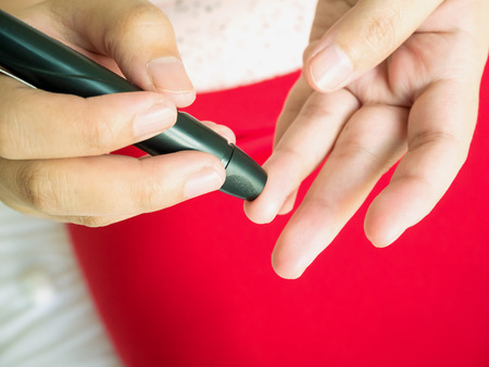 woman using lancelet on finger, diabetes test checking blood sugar levelの写真素材