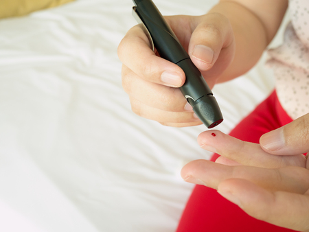 woman using lancelet on finger, diabetes test checking blood sugar levelの写真素材
