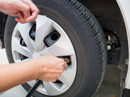 man filling air pressure in the car tyre close upの写真素材