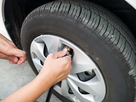 man filling air pressure in the car tyre close upの写真素材