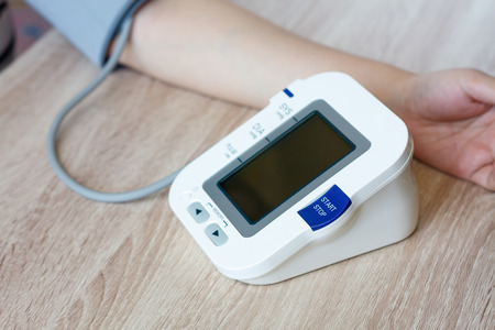 Woman using digital blood pressure monitor to measures her blood pressureの写真素材