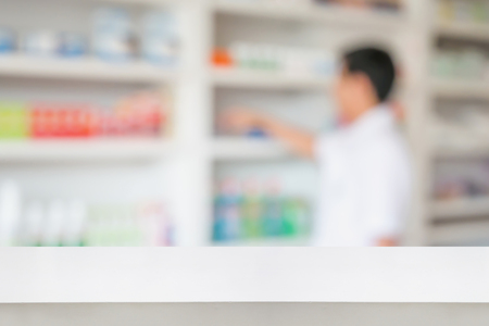 Blank white pharmacy table counter with blur shelves of drug in the pharmacy drugstore background, For create montage medical product displayの写真素材