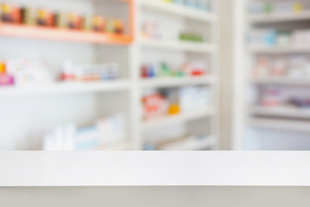 Blank white pharmacy table counter with blur shelves of drug in the pharmacy drugstore background, For create montage medical product displayの写真素材