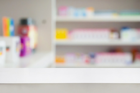 Blank white pharmacy table counter with blur shelves of drug in the pharmacy drugstore background, For create montage medical product displayの写真素材