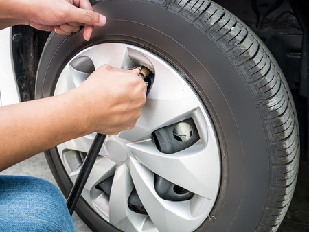 man filling air pressure in the car tyre close upの写真素材