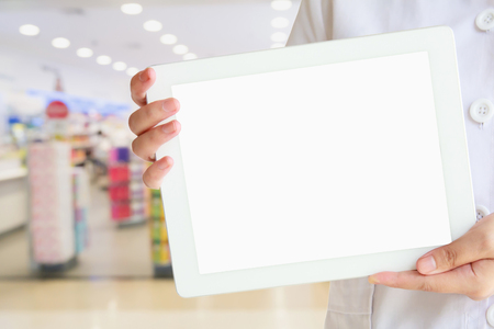 Pharmacist showing blank digital tablet computer with the pharmacy health care store blur backgroundの写真素材
