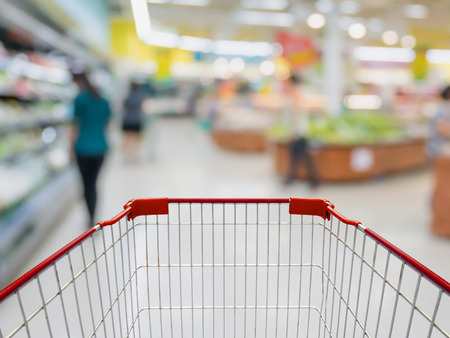 Shopping cart with Grocery store blur background with customersの写真素材