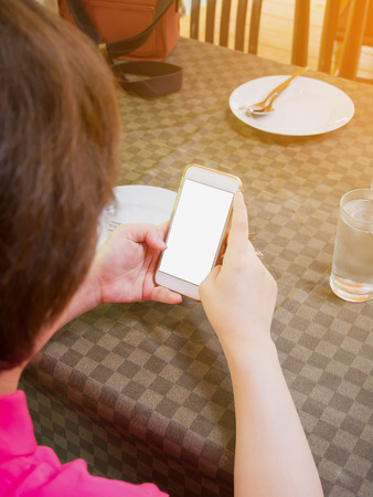 woman with mobile smart phone in her hands over restaurant tableの写真素材