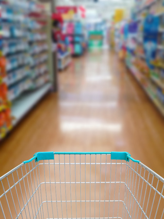supermarket shelves aisle blurred background with shopping cartの写真素材