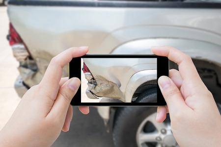 woman using mobile smartphone take photo car crash accident of the damage to the car for accident insuranceの写真素材