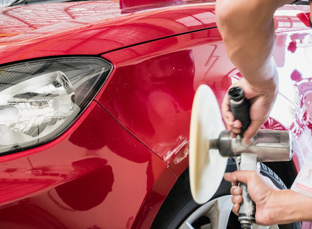 Worker cleaning the car with polishing and waxing the red carの写真素材