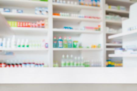 Blank white pharmacy table counter with blur shelves of drug in the pharmacy drugstore background, For create montage medical product displayの写真素材
