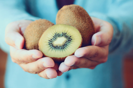 holding fresh kiwi fruit in hands vintage toneの写真素材