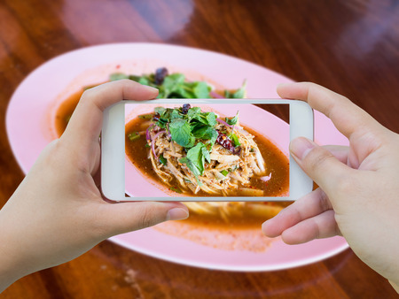 taking photo of Bamboo shoot spicy salad Thai food with smartphoneの写真素材