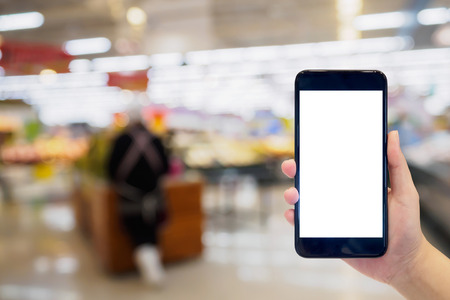 Woman hold mobile phone while shopping in supermarketの写真素材
