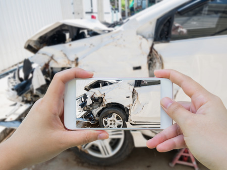 Female using mobile smart phone taking photo of the car crash accident damage for insuranceの写真素材
