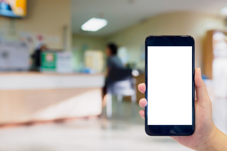 hand hold mobile smartphone with blur hospital interior for backgroundの写真素材