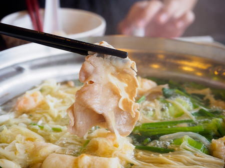 Sukiyaki or Shabu shabu pork slice in chopsticks over hot potの写真素材