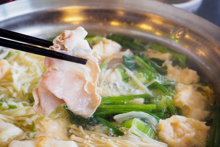 Sukiyaki or Shabu shabu pork slice in chopsticks over hot potの写真素材