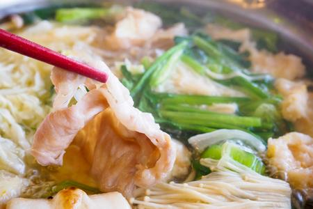 Sukiyaki or Shabu shabu pork slice in chopsticks over hot potの写真素材