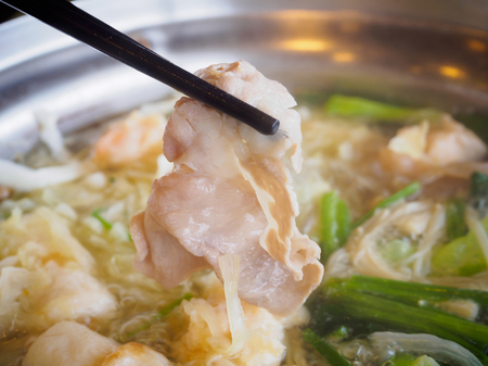 Sukiyaki or Shabu shabu pork slice in chopsticks over hot potの写真素材