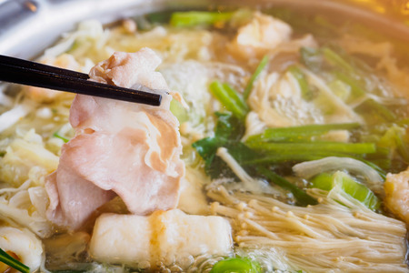 Sukiyaki or Shabu shabu pork slice in chopsticks over hot potの写真素材