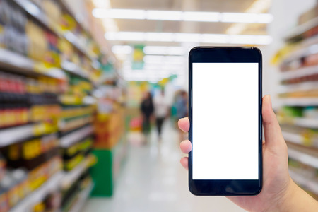 Woman hold mobile phone while shopping in supermarketの写真素材