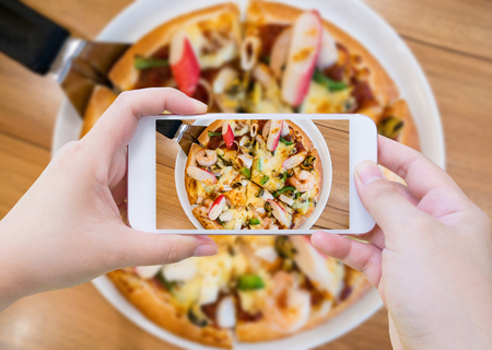 woman taking photo of Pizza with mobile smartphoneの写真素材