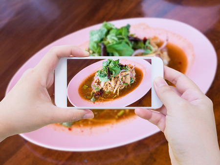 taking photo of Bamboo shoot spicy salad Thai food with smartphoneの写真素材