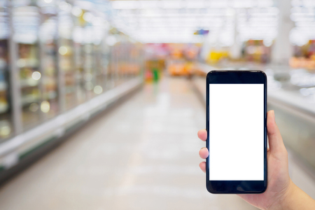 Woman hold mobile phone while shopping in supermarketの写真素材