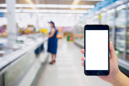 Woman hold mobile phone while shopping in supermarketの写真素材