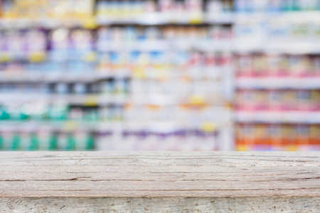 Abstract blur supermarket shelves background with wood tableの写真素材