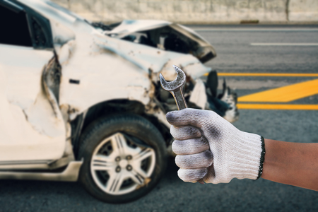 mechanic hand hold wrench with car crash accident damage background, auto body repair conceptの写真素材