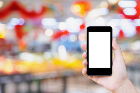 Woman using mobile smartphone while shopping in supermarket storeの写真素材