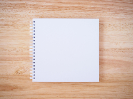 blank white cover notebook top view on brown wood desk table backgroundの写真素材