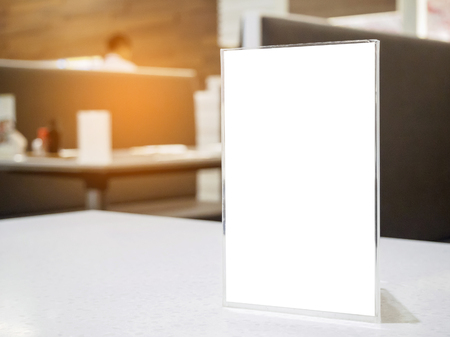 Mock up menu frame on table in the cafe restaurant, acrylic stand with white paperの写真素材