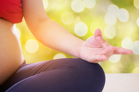 pregnant woman doing yoga with nature bokeh backgroundの写真素材