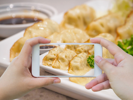 taking photo of Gyoza dumplings with smartphoneの写真素材