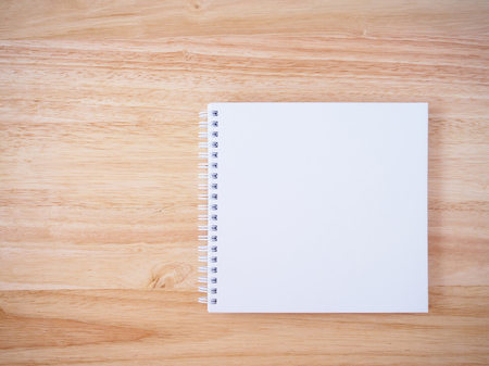 blank white cover notebook top view on brown wood desk table backgroundの写真素材