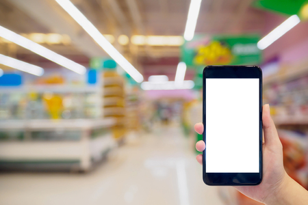 Woman hold mobile phone while shopping in supermarketの写真素材