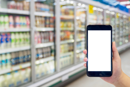 Woman hold mobile phone while shopping in supermarketの写真素材