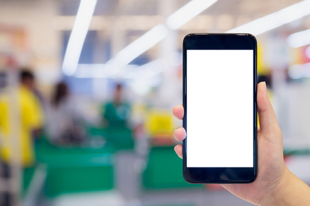 Woman hand holding mobile phone at supermarket checkout background, digital wallet conceptの写真素材