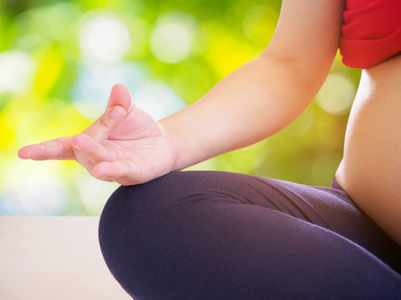 pregnant woman doing yoga with nature bokeh backgroundの写真素材